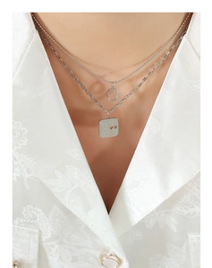Close-up of layered silver titanium steel necklace with engraved You & Me square pendant