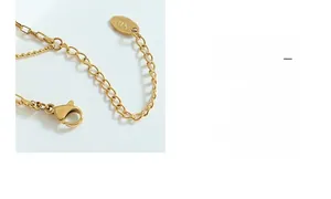 Detailed macro of the lobster clasp and K18 engraved tag on the gold-plated chain