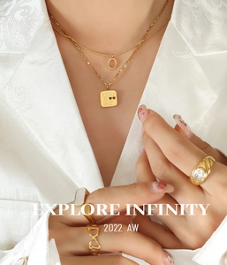 Detail of layered gold titanium necklace with You & Me square pendant on a female model