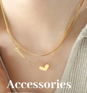 Detail of layered gold necklaces with Love tag and heart pendant on a knitted sweater