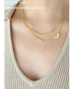 Detail of layered gold snake chain necklace with Love letter and heart pendants on neck