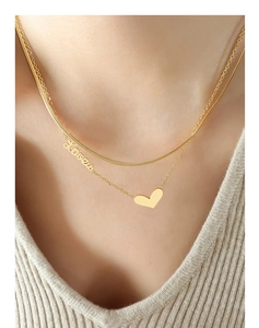 Close-up of double-layer gold necklace featuring heart pendant and Love engraving