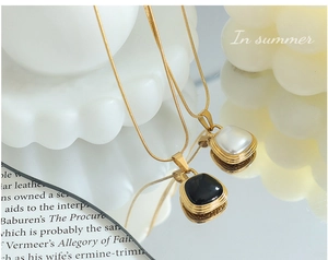 Detail of luxury gold snake chain necklaces with black and white pearl square pendants
