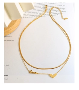 Detail of gold double-layered necklace featuring a Love script charm and heart pendant