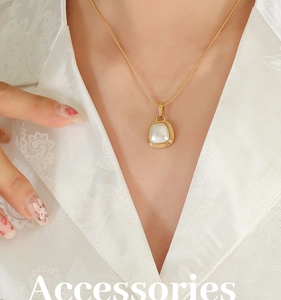 Detail of gold snake chain necklace with square pearl pendant on a model in white silk