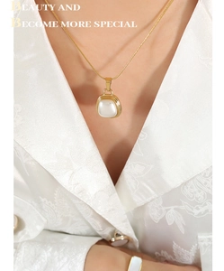 Close-up of elegant gold snake chain with white pearl pendant on model neck
