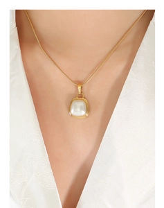 Detail of elegant gold snake chain necklace featuring a square pearl pendant on a model