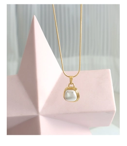 Detail of a minimalist gold necklace with a white square pendant on a star-shaped stand