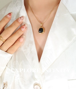 Close-up of elegant gold snake chain necklace with black square pendant on a model
