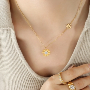 Ensemble collier marguerite dorée et bagues en cristal sur un mannequin en tricot