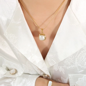 Elegant gold snake chain necklace with a square pearl pendant on a female model