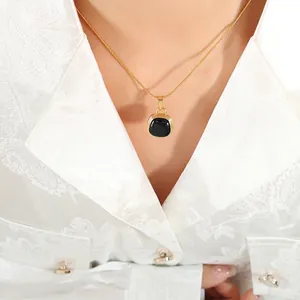 Elegant gold snake chain necklace with black square pendant on white satin background