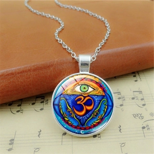Gros plan du pendentif symbole Om et Œil du Mal sur partition vintage et cuir