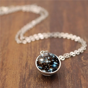 Collier boule de verre galaxie double face avec chaîne argentée sur fond en bois naturel