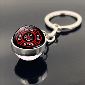 Close-up of a silver firefighter keychain with a glass dome featuring a Fire Dept logo