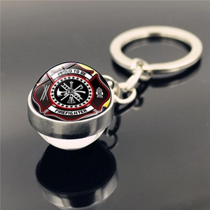 Close-up of a silver firefighter badge keychain with glass dome and cross symbols