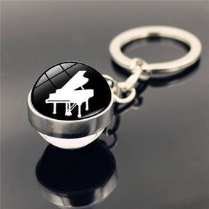 Porte-clés piano en verre et métal poli sur fond miroir avec pendentif minimaliste