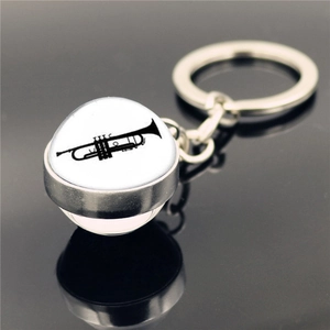 Macro d'un porte-clés musical argenté avec pendentif en verre et silhouette de trompette