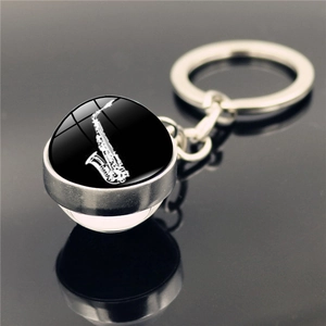 Vue macro d'un porte-clés saxophone en argent avec cabochon en verre sur surface noire