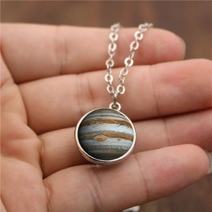 Hand holding a double-sided solar system Jupiter glass ball pendant with silver chain