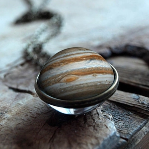 Macro shot of solar system Jupiter glass pendant with antique bronze chain on wood