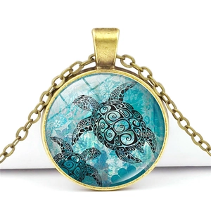 Detail of round bronze necklace featuring sea turtle pattern under glass dome