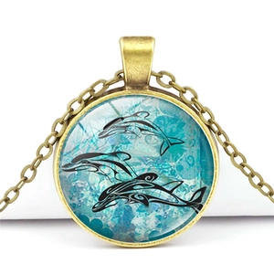 Detailed macro of a dolphin time gem pendant with blue ocean glass and bronze chain