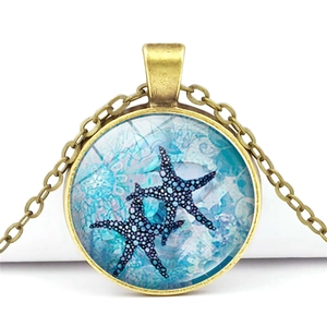 Detail of vintage bronze starfish necklace with blue ocean glass gem pendant