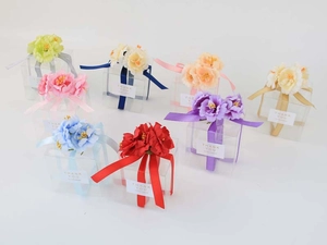 Detailed view of clear PET gift boxes with colorful silk flowers and Thank You ribbons