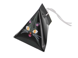 Detalle de caja de dulces de gato negro triangular con ojos naranjas y cinta