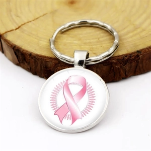 Silver metal keychain with pink ribbon breast cancer awareness pendant on wood block