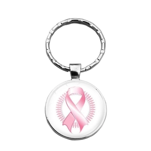 Close-up of a metal keychain with pink ribbon charm and smooth glass cabochon finish
