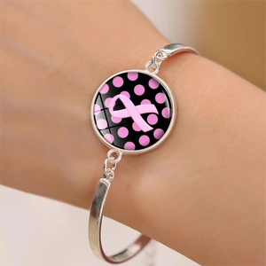 Vue macro d'un bracelet argenté avec pendentif en verre et ruban rose de sensibilisation