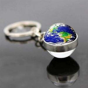 Vue macro du porte-clés globe en verre avec base en métal argenté et pendentif planète