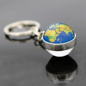 Gros plan d'un porte-clés globe terrestre en métal argenté avec carte du monde sur fond sombre