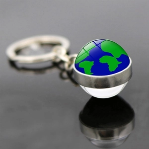 Porte-clés terre avec pendentif boule de verre se reflétant sur une surface sombre et lisse