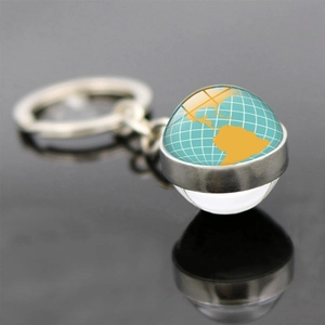 Porte-clés globe terrestre avec chaîne en métal et dôme en verre sur surface réfléchissante