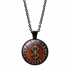 Detail shot of Viking rune pendant necklace with golden runic compass on brown background