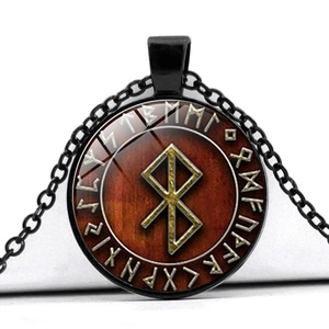 Macro detail of Nordic rune pendant with red wood texture and black alloy chain
