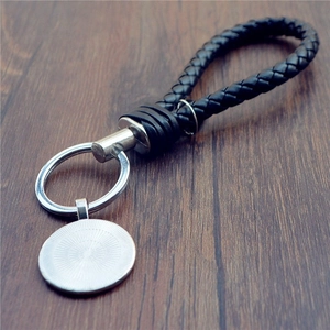 Braided leather evil eye keychain in black with silver metal ring on wood background
