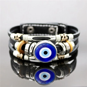 Handmade multilayer leather bracelet featuring a blue evil eye bead and silver charms