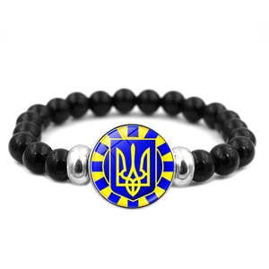 Primer plano de pulsera de cuentas negras con dije del escudo de Ucrania en fondo blanco