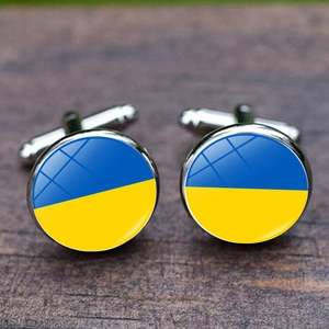 Polished silver cufflinks with Ukraine flag design under glass on wood background