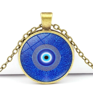Detailed close-up of a blue evil eye glass pendant on a bronze alloy necklace chain