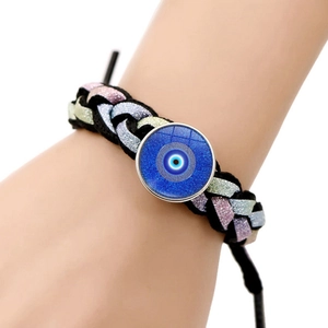 Detail of hand-woven black cord bracelet with gradient blue Evil Eye pendant charm