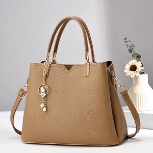 Detail of brown lychee leather tote bag with rabbit charm and pearl tassel accessories