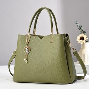 Detail of olive green lychee leather handbag with golden hardware and cute bunny charm