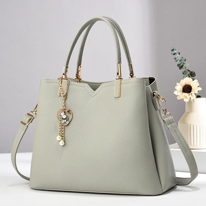 Detail of light green litchi grain leather bag with golden hardware and rabbit charm