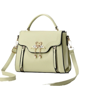 Pistachio green textured leather handbag with gold swan clasp and pearl pendant
