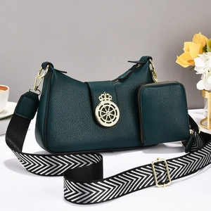 Detalle de bolso en cuero granulado verde oscuro con logo dorado y correa chevron